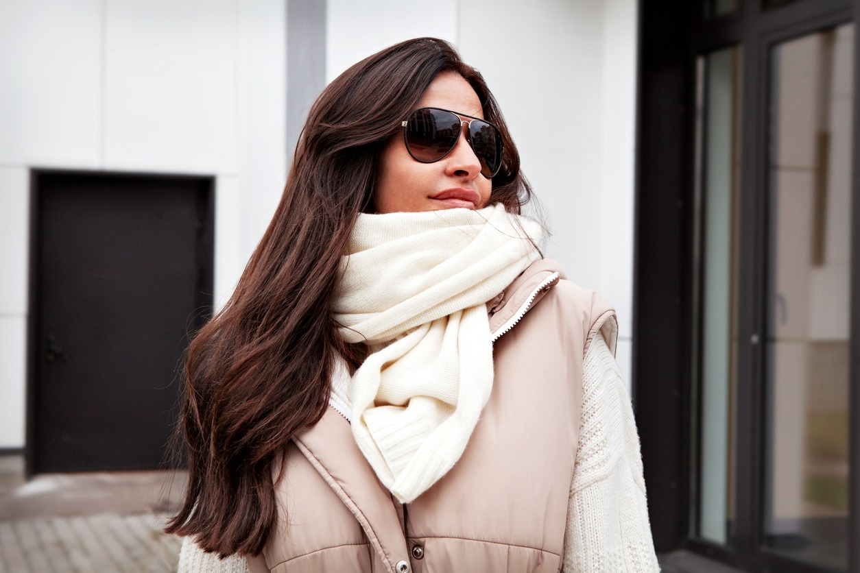 A woman wearing a knitted scarf, sweater, and vest