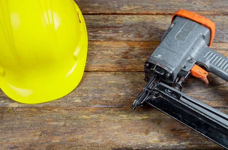 A nail gun beside a hard hat