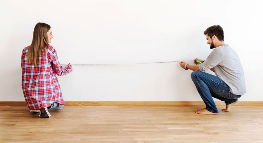 A couple measuring the walls