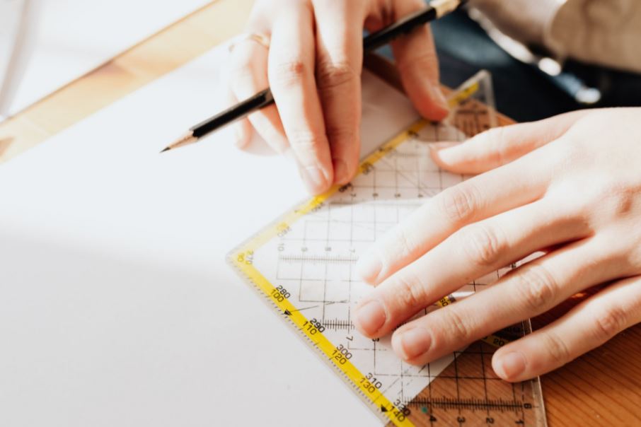 person using ruler on a white piece of paper