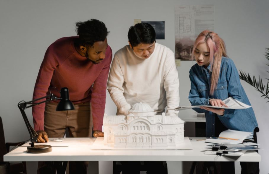 three people discussing with an architectural model before them
