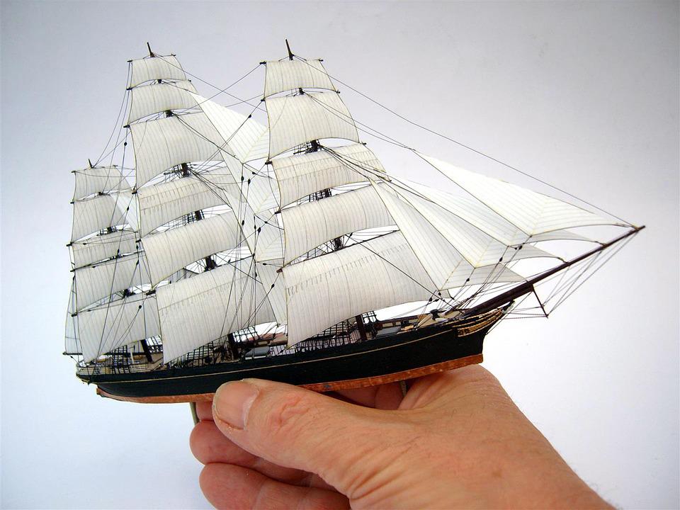 a close up of a person’s hand holding a small model ship