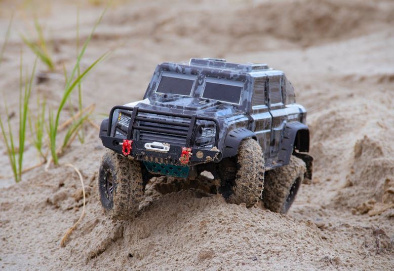 a close up shot of an RC car on the sand