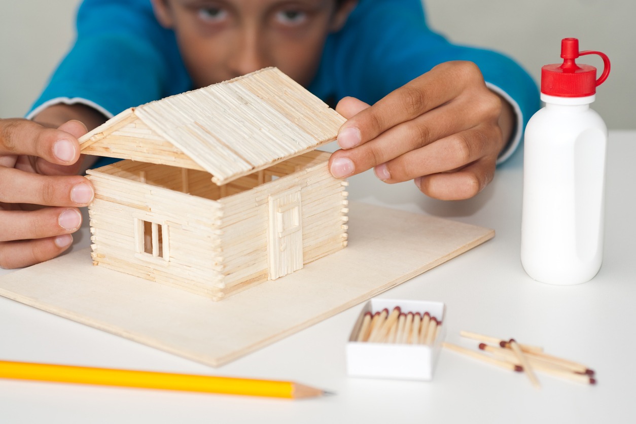 a child assembling a wooden house