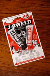 a package of J-B Weld, showing 'hardener' (red tube) and 'steel' (black tube of resin)