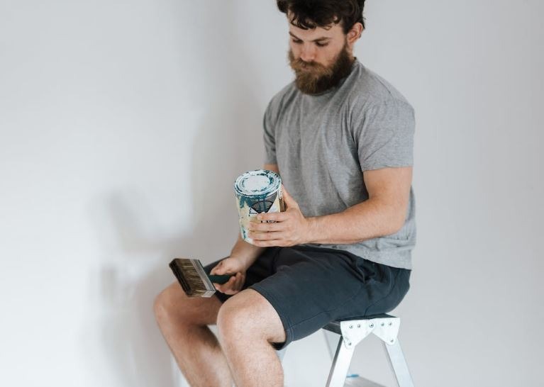 A man looking at a paint can