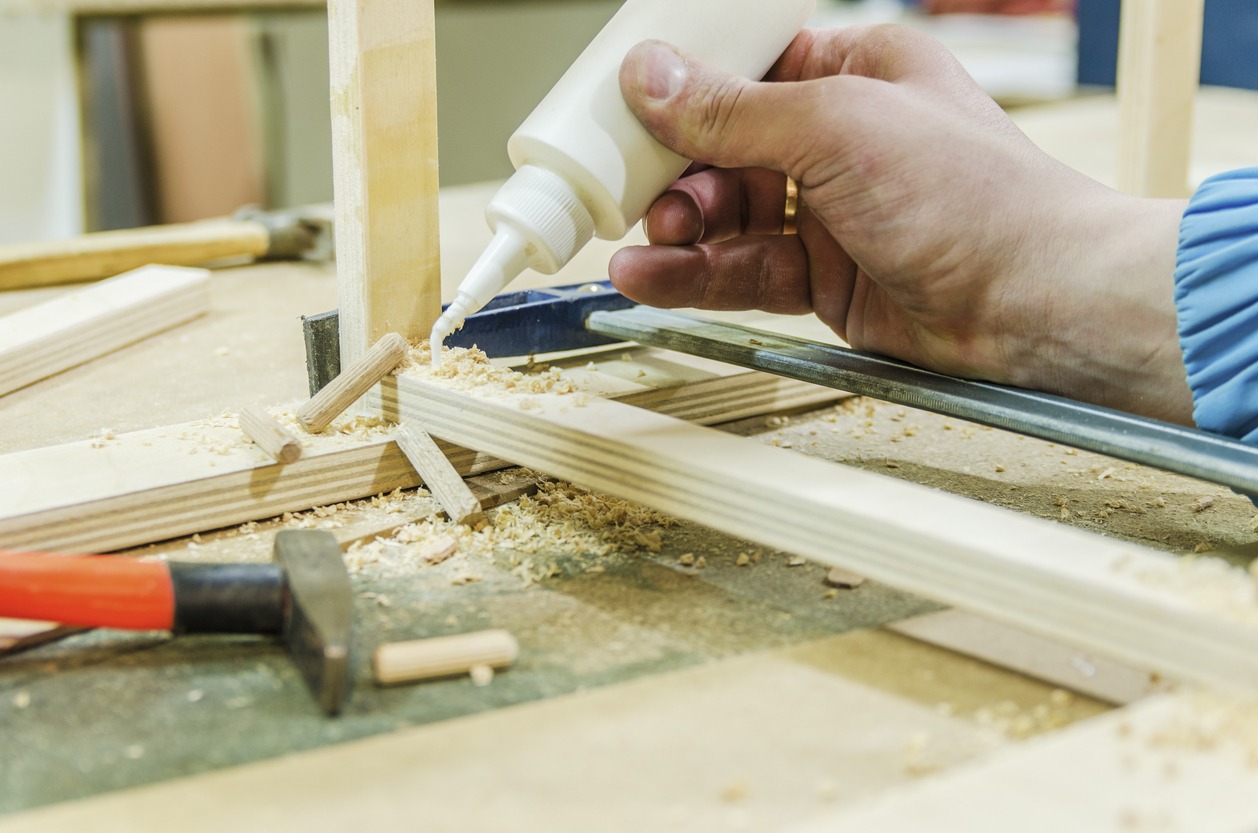 a hand applying white glue on wood