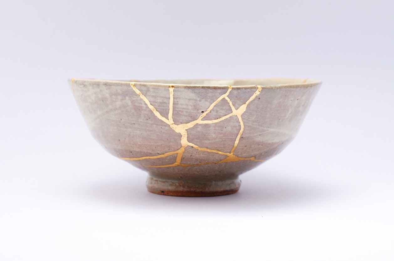 Kintsugi beige bowl. Gold cracks restoration on old Japanese pottery restored with the antique Kintsugi restoration technique. The beauty of imperfections. japanese pottery repair gold. japanese art of repairing cracks with gold. japanese art of fixing broken pottery