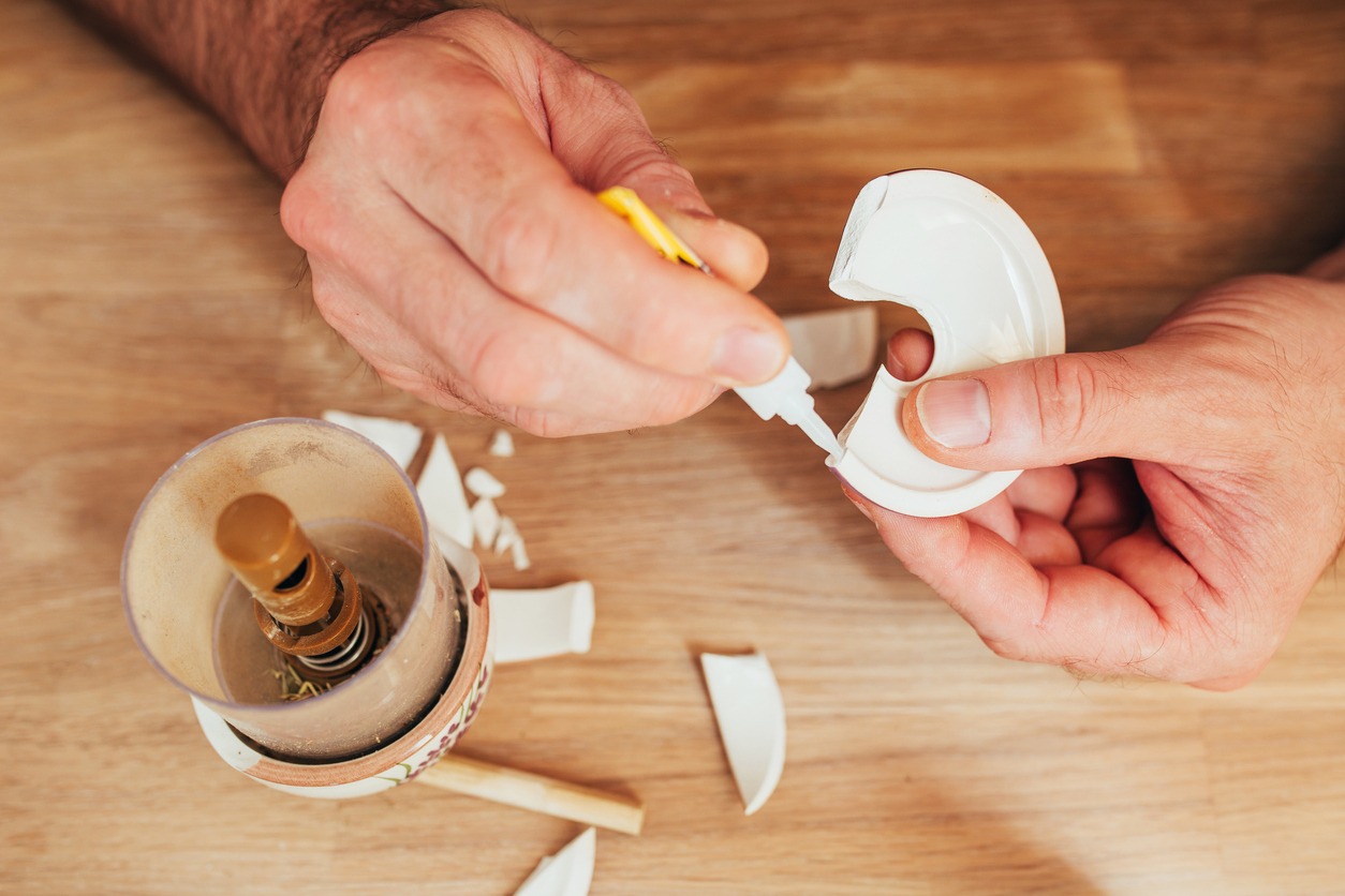 man fixing a broken ceramic item using a small tube of glue