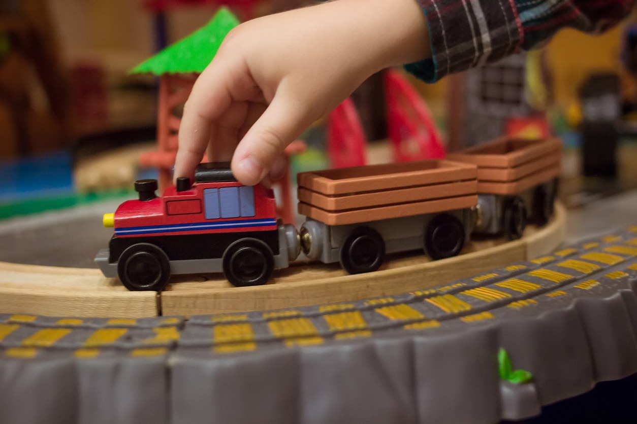 hand of a child pushing a wooden model train toy