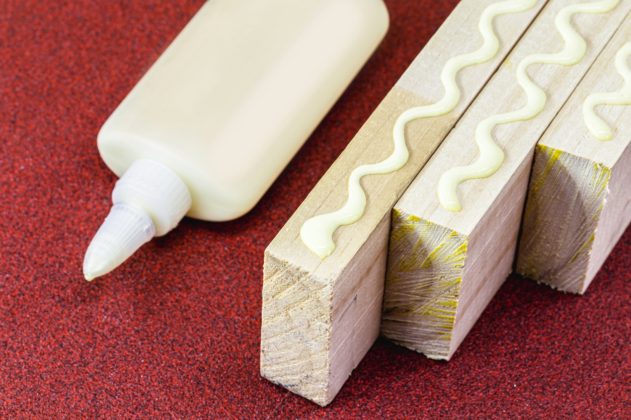 a wood glue on sandpaper beside wooden blocks with swirls of glue on them