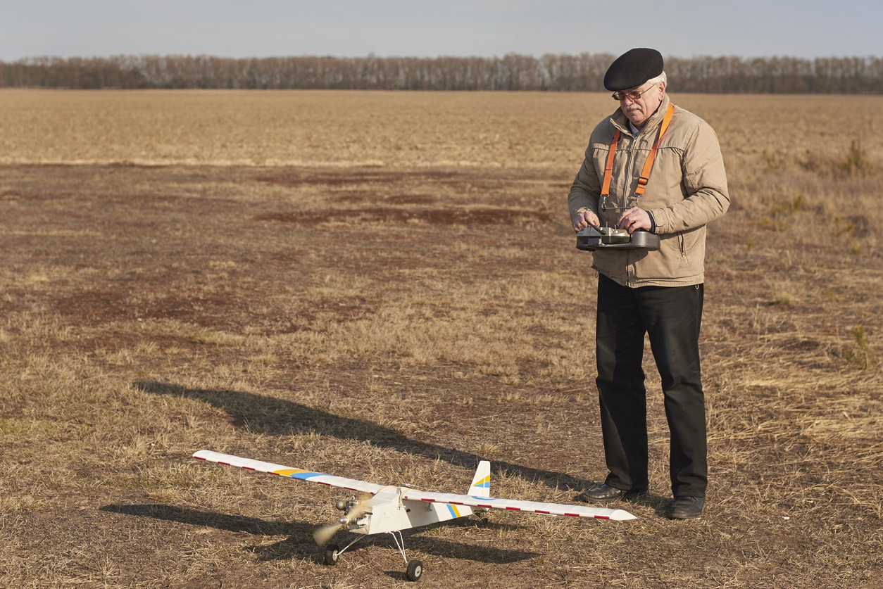 man controls a radio-controlled aircraft on the field