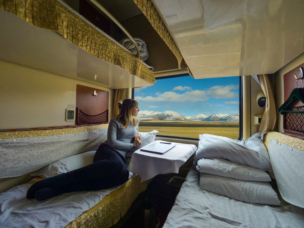 Young woman lies on the bed and looks through the window of the sleeper train