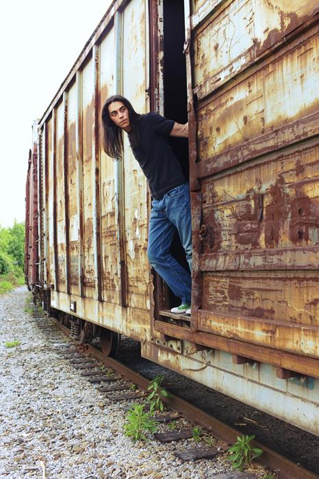 A native American looks out from a freight car while riding the rails