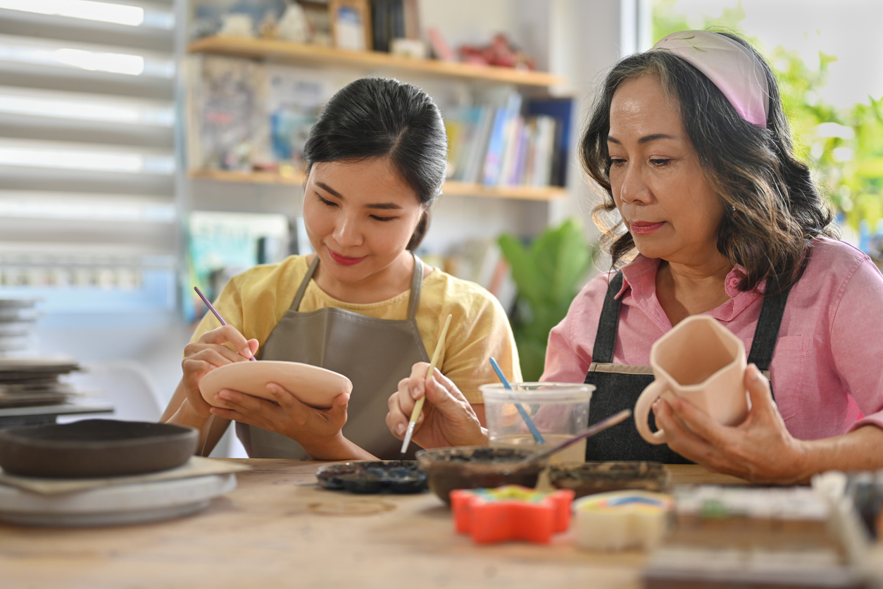 a mother and daughter painting ceramic crockery