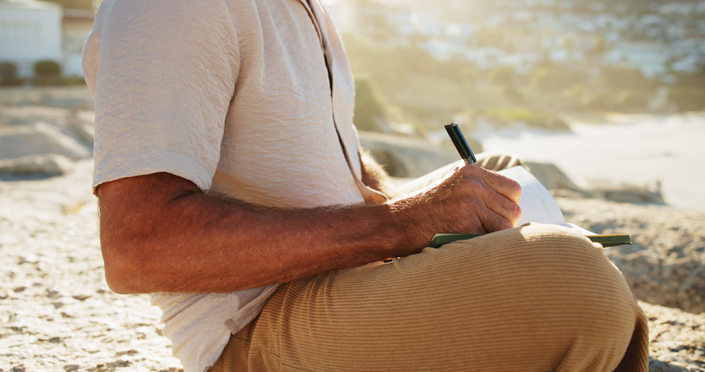 Hands, man outdoor and writing with diary, personal development plan and goal setting for inspiration. Daily reflection, notes and person with journal, mindfulness and insight for self-improvement