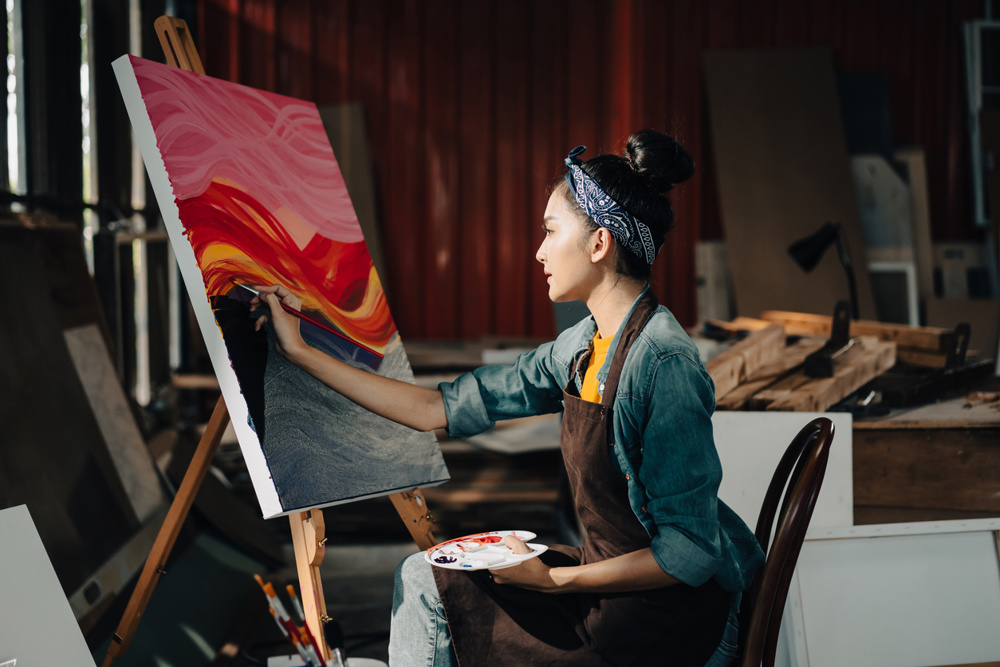 Asian Female Artist Draws create art piece with palette and brush painting at studio