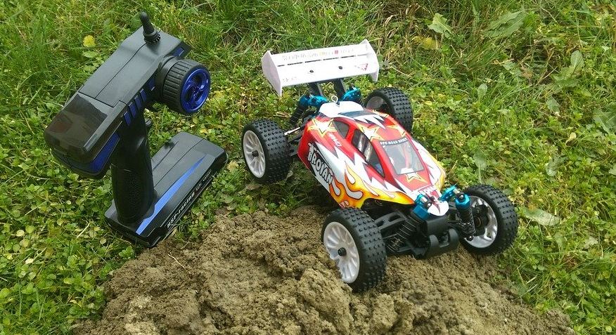an RC toy car and its black controller on the ground
