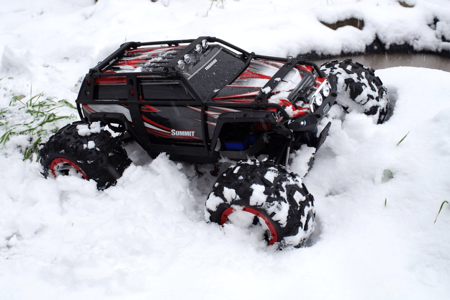 black-and-red RC toy car tearing through the snow