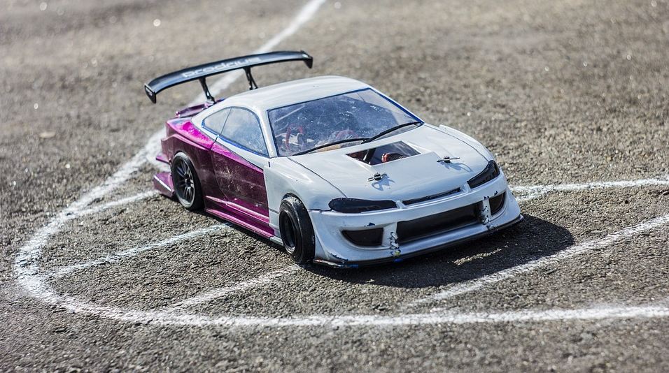 a white RC car on a concrete surface with white linings